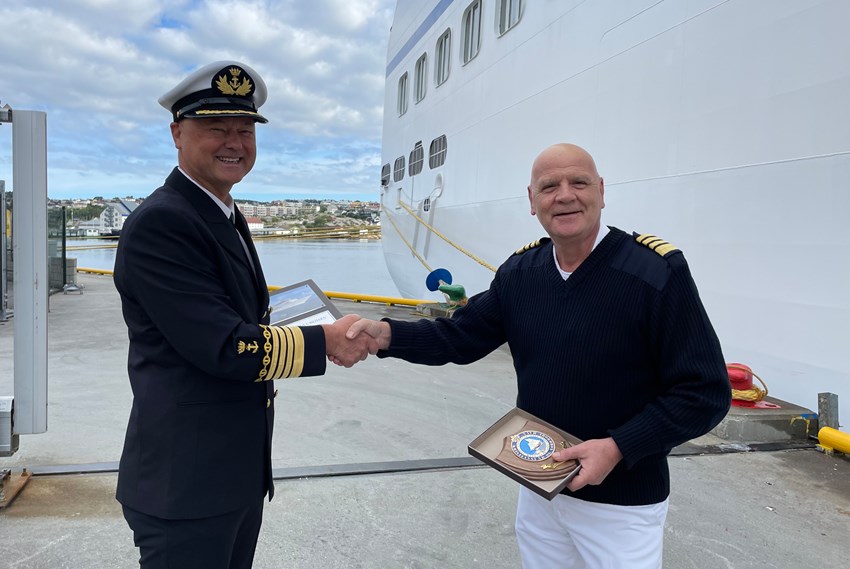 Havnefogd Knut Mostad og kaptein Atanas Georgiev Kostadinov på cruiseskipet «Sirena» håndhilser og utveksler plakett. Foto.