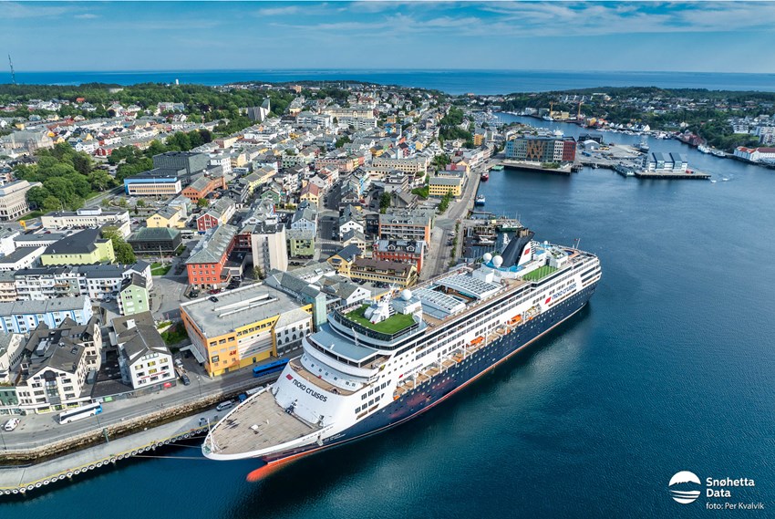 Cruiseskip til kai i Kristiansund med sentrum og blå himmel i bakgrunn. Foto.