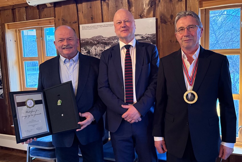 Tre menn i dress med diplom og medaljer. Foto.