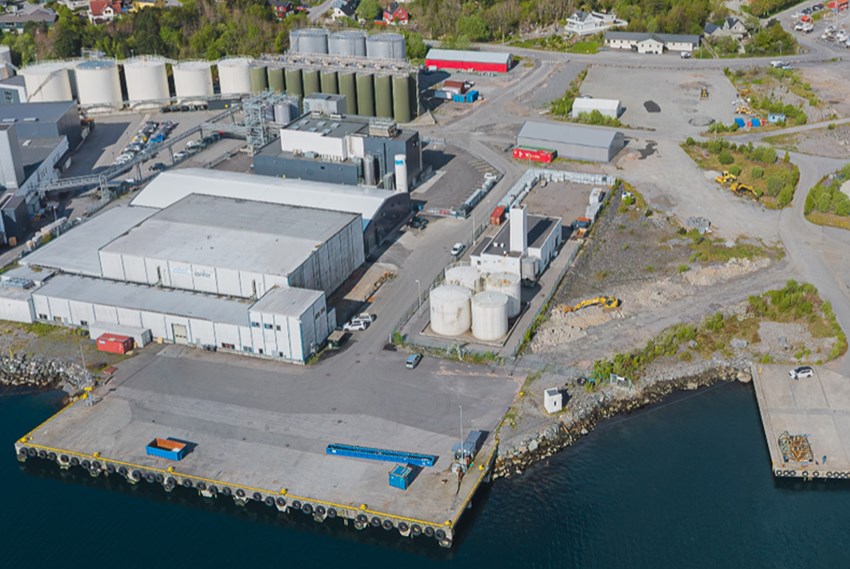 Industriområde med lagerbygg, tanker, kaier. Foto.