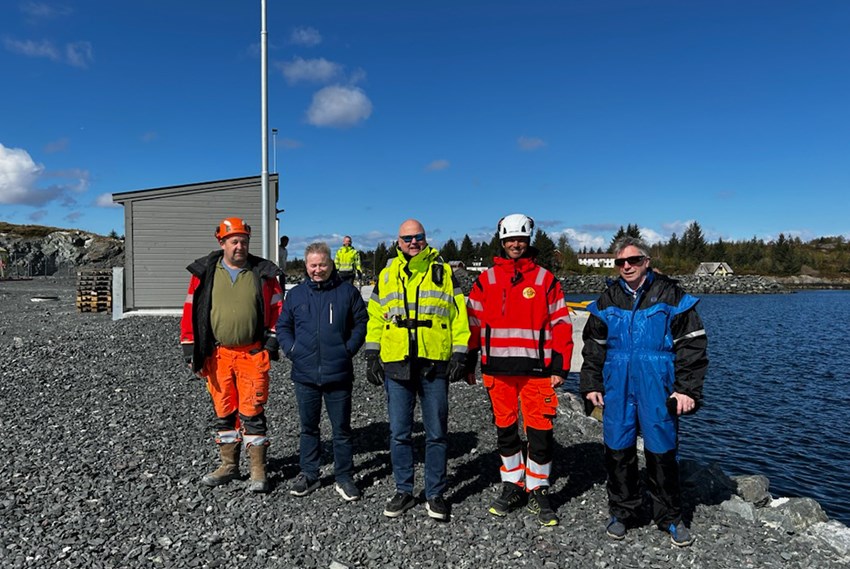 Gruppe med mennesker i arbeidstøy på kaikant. Foto.